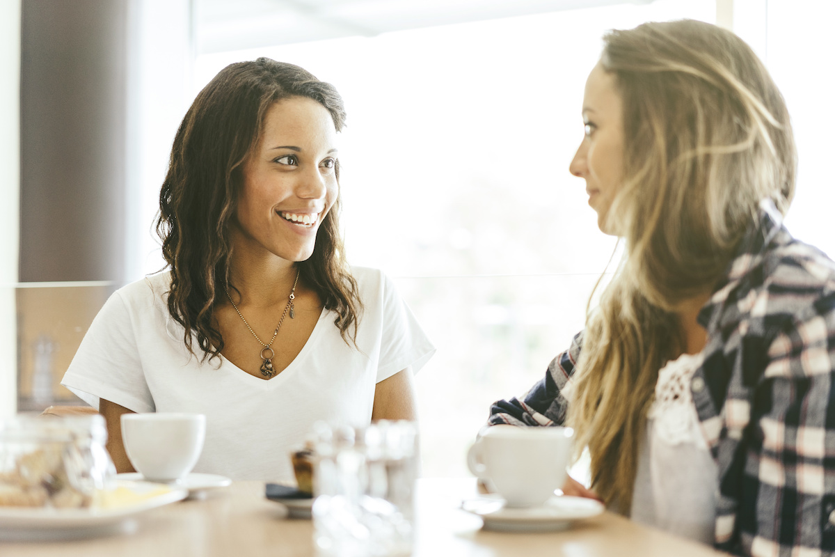 two young girls talking in a brightly lit cafeteria